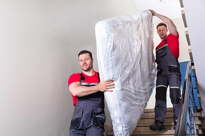 two people carrying a box spring out of a room in Campbelltown PA